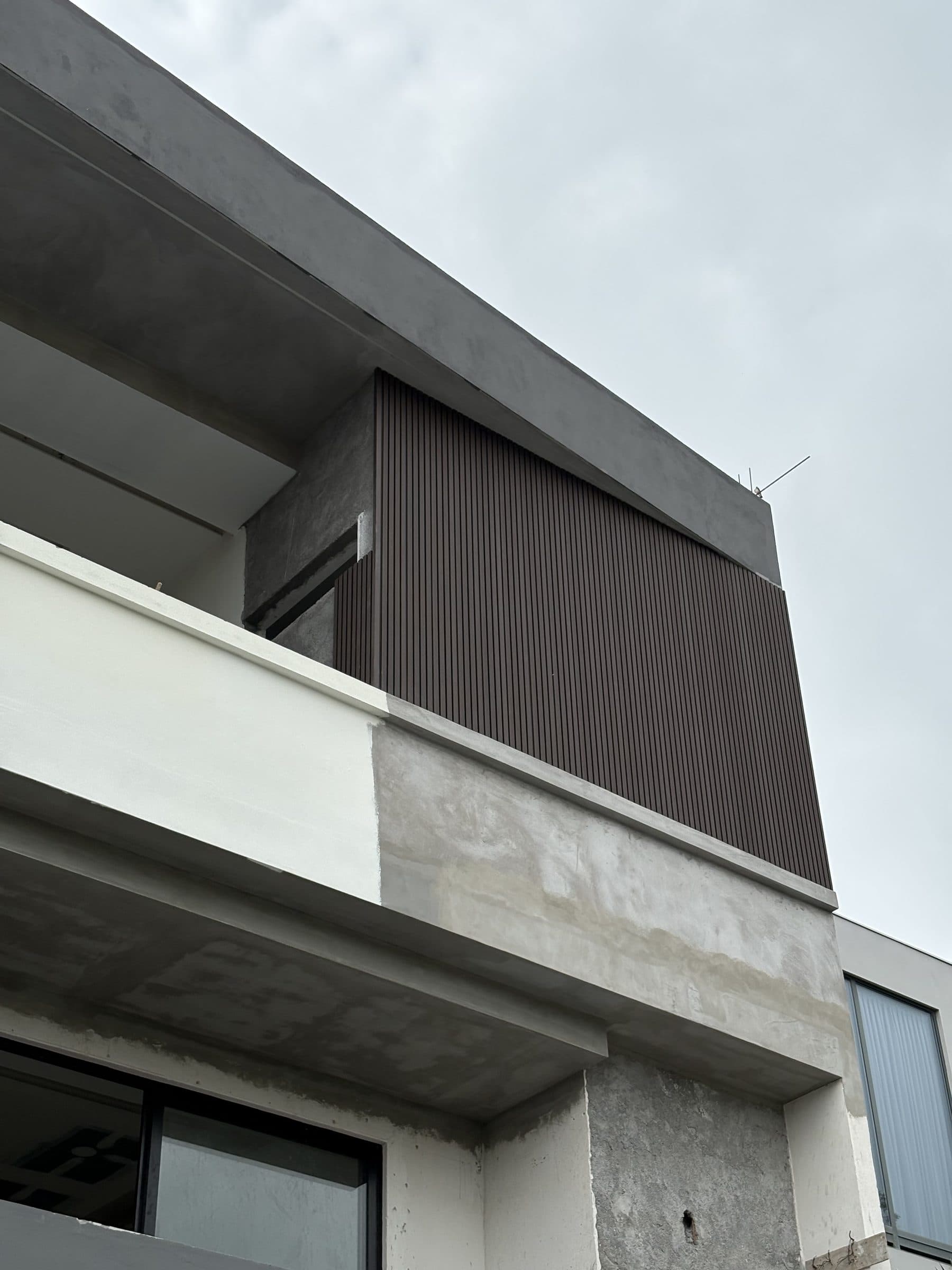 Fachada de concreto con plafón exterior de listones WPC color chocolate