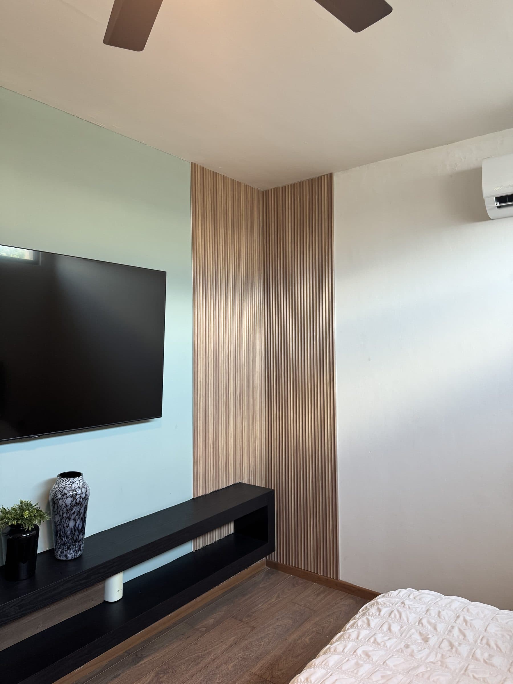 Muro de TV con lambrín WPC claro y mueble flotante en recámara